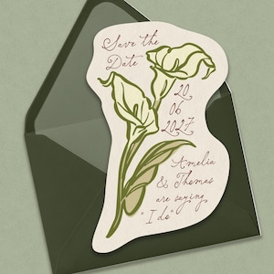 May include: A die-cut save the date card featuring a green calla lily illustration and cursive text that reads Save the Date, 20 06 2027, Amelia & Thomas are saying I do, placed on top of a dark olive green envelope with a triangular flap.