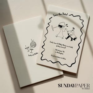 May include: Two off-white wedding invitation cards. One card has a disco ball and two champagne glasses. The other card has a black border and a cartoon of a couple with the text "Save the Date!" and wedding details.