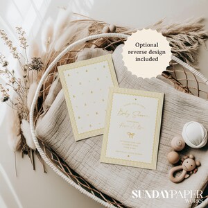 Może przedstawiać: Zaproszenia na baby shower w miękkich odcieniach ż&oacute;łci i bieli. Zaproszenia mają wz&oacute;r pszcz&oacute;ł i elegancki kr&oacute;j pisma. Widoczny jest tekst "Optional reverse design included". Zaproszenia są prezentowane z zabawkami dla dzieci i elementami dekoracyjnymi.
