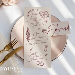 Op de afbeelding: Een menukaart en een naambordje met de naam "Edward" in bordeauxrood schrift worden weergegeven op een roze bord. Het menu bevat voorgerechten, hoofdgerechten en desserts met illustraties. Een gouden vork en mes liggen op een witte servet.