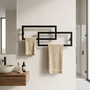 Peut inclure: Un porte-serviettes moderne en métal noir avec un design géométrique, tenant deux serviettes beiges. Le porte-serviettes est fixé sur un mur blanc dans une salle de bain, avec un lavabo et un miroir en arrière-plan.