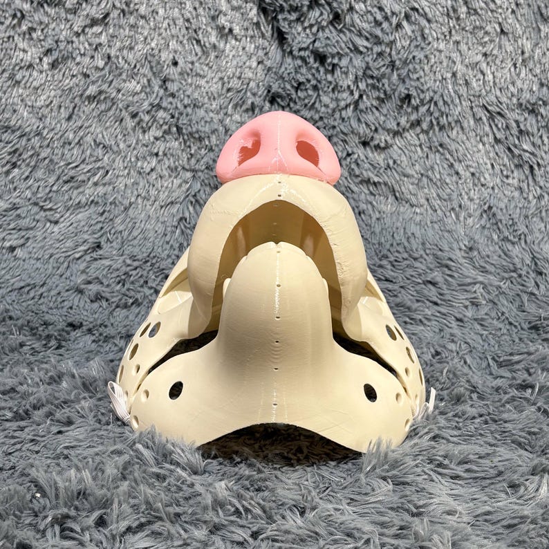 Canine fursuit head base inspired by wolves and fantasy K9 characters. Features a moving jaw hinge for expressive motion and realism. Made from durable 3D printed PLA plastic, this base is perfect for furry costume makers, Halloween cosplay, or anthro and kemono-themed DIY projects. Smooth finish ready for decorating.