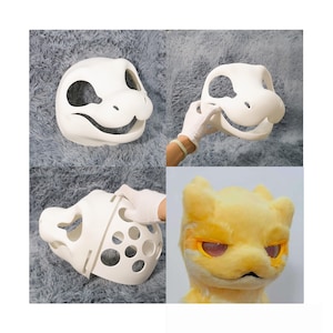 Może przedstawiać: Biała, niedokończona maska w kształcie dinozaura z dużymi otworami na oczy i uśmiechniętymi ustami. Maska jest pokazana na wielu etapach montażu. Pokazana jest również gotowa, pluszowa, żółta głowa z pomarańczowymi oczami.