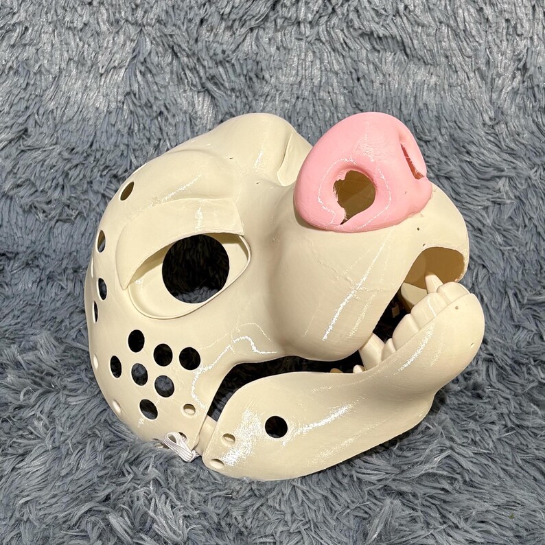 A cartoon-style Dire Mask canine fursuit head base, featuring a functional hinged jaw for animated movement and a playful stylized design. 3D printed using durable PLA, this base is perfect for DIY furry costume builds, Halloween wolf characters, or kemono cosplay projects. Its smooth surface allows for easy customization, sanding, and decoration to bring your creation to life.