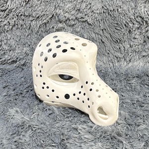 May include: White, unpainted, 3D printed animal mask with a textured surface and a series of small holes. The mask has a large eye opening and a snout.