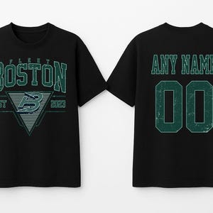May include: Black t-shirts with a distressed green design. The front shirt displays "BOSTON" with a triangle graphic and "EST 2023". The back shirt has "ANY NAME" above the number "00".