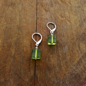 Puede incluir: Un par de pendientes de plata con cuentas cuadradas de vidrio verde.