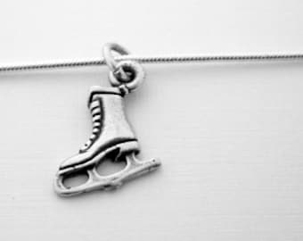 Peut inclure: Un pendentif en argent en forme de patins à glace suspendu à un collier en chaîne argentée. Le pendentif est détaillé avec une botte et une lame.