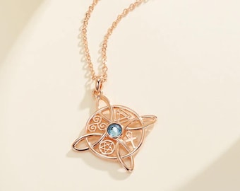 May include: Rose gold necklace featuring a Celtic knot pendant with a central blue gemstone. The pendant has intricate knotwork and symbols. The chain is delicate and the necklace is displayed on a white surface.