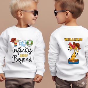 Puede incluir: Sudadera blanca con el texto "TWO infinity AND Beyond" en la parte delantera. El dise&ntilde;o incluye un sombrero de vaquero y el n&uacute;mero 2. La parte trasera de la sudadera tiene el nombre "WILLIAM" y un dise&ntilde;o del n&uacute;mero 2.