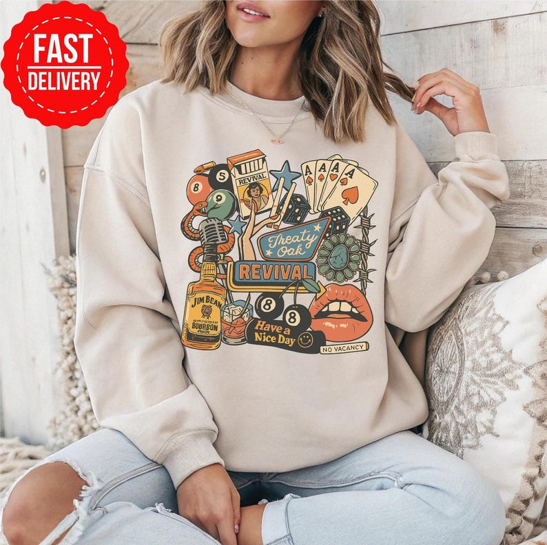 Peut inclure: Sweat-shirt beige avec un motif color&eacute;. Le motif comprend une bouteille de bourbon Jim Beam, des cartes &agrave; jouer, des d&eacute;s et les mots "Treaty Oak Revival" et "Have a Nice Day". Le motif comprend une paire de l&egrave;vres et une boule de billard.