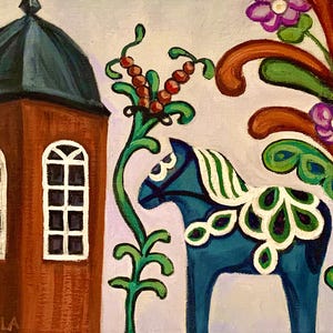May include: An original painting depicting a blue Dala horse with white and green details, a brown building with arched windows, and vibrant floral motifs. The artwork is signed "GUNILLA". The background is a light purple colour.