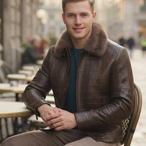 May include: A brown jacket with a textured crocodile-skin pattern and a thick, plush brown fur collar. The jacket features a front zipper closure and is worn over a dark teal shirt, paired with light brown trousers.
