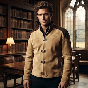 May include: A tan suede jacket featuring a high collar, dark brown shoulder panels, and four metallic toggle closures down the front. The jacket is worn over a black collared shirt and paired with black trousers, creating a structured look.