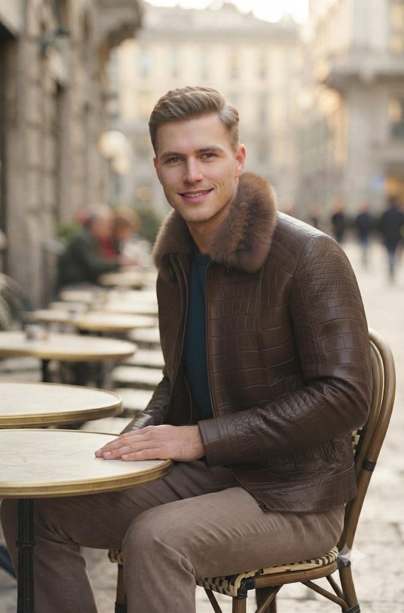 May include: A brown leather jacket with a textured crocodile-skin pattern and a thick, plush fur collar. The jacket features a front zipper closure and long sleeves, worn over a dark blue shirt paired with light brown trousers.