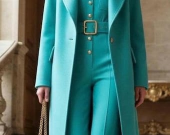 May include: A vibrant turquoise long coat worn over a matching turquoise jumpsuit featuring a button-down front, a belted waist with a gold-toned buckle, and wide-leg trousers. The ensemble is paired with a small yellow handbag and turquoise pumps.