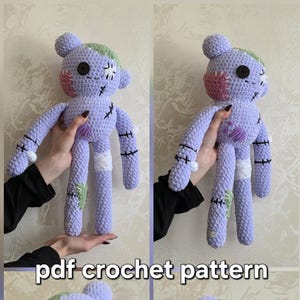 May include: A lavender crochet plush toy featuring a green patch on the head, a pink cheek patch, and black stitched details resembling scars. The toy has a black button eye and white fabric accents. The text pdf crochet pattern is visible.
