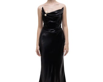 May include: A black strapless gown with a draped bodice and a fitted skirt. The gown has a pearl embellishment on the bodice.