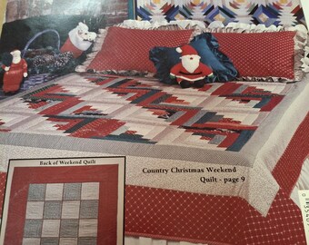 May include: A magazine page featuring a Christmas-themed quilt. The quilt has a red, gray, and white color scheme. The text "Country Christmas Weekend Quilt - page 9" is visible. A small Santa Claus doll is on the bed.