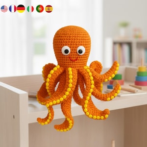Puede incluir: Un juguete de pulpo tejido a ganchillo de color naranja con detalles amarillos. El pulpo tiene grandes ojos blancos, una boca roja sonriente y ocho tentáculos rizados. Los tentáculos están adornados con bolitas amarillas. Juguete infantil.