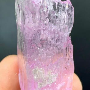 May include: A pink and clear crystal with a layered, faceted structure. The crystal is translucent and has a slight shimmer.