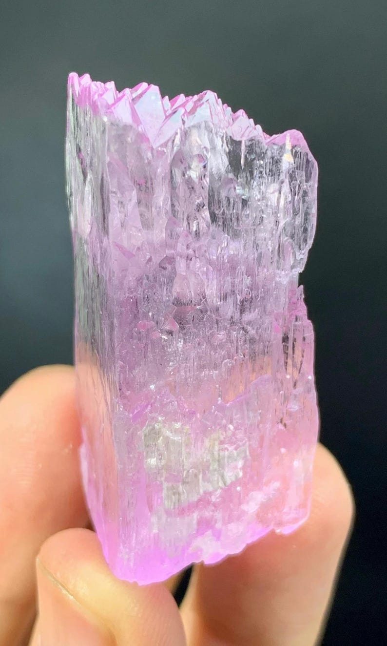May include: A pink and clear crystal with a layered, faceted structure. The crystal is translucent and has a slight shimmer.
