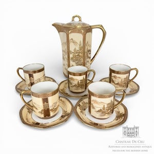 Puede incluir: Un juego de té vintage con una cafetera color crema y tazas y platillos a juego. El juego está adornado con detalles dorados y escenas de paisajes. El juego incluye una cafetera, cinco tazas y cinco platillos.