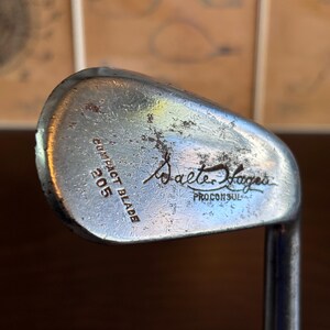 Puede incluir: Un palo de golf plateado con el texto "Walter Hagen Pro Consul Compact Blade 205" en la cara.