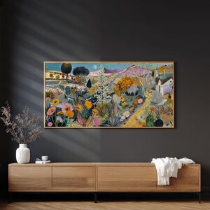 May include: A framed landscape painting depicts a vibrant garden scene with colorful flowers, trees, and a distant mountain range. The artwork features a variety of hues, including pink, yellow, green, and blue, creating a lively and detailed composition. The painting is displayed above a wooden cabinet.