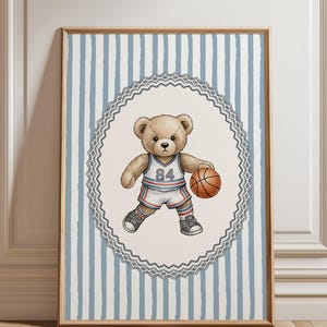 May include: A framed print featuring a teddy bear in a basketball uniform, holding a basketball. The bear wears a white and blue jersey with the number 84. The background has blue and white vertical stripes, framed in a wooden frame.