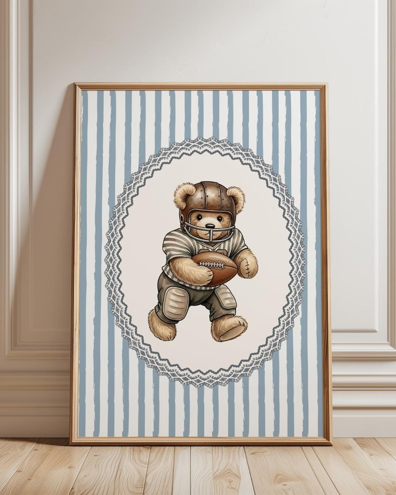 May include: A framed print featuring a teddy bear in a football uniform, including a helmet and pads, holding a football. The bear is set against a light blue and white striped background, framed by a decorative oval border.
