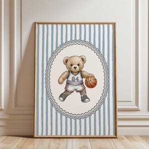 May include: Framed art print featuring a teddy bear in a basketball uniform, holding a basketball. The artwork is set against a blue and white striped background, with a decorative border. The text "The Cutest Vintage Sports Teddy Bear Art" is displayed.