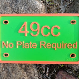 May include: Green license plate with an orange border. The plate says "49cc No Plate Required" in orange text.