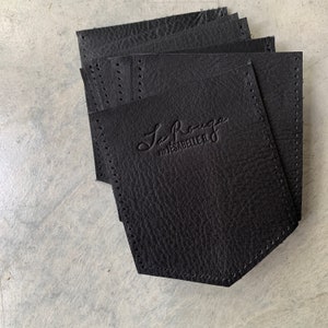 May include: A stack of black leather pocket squares with the text "La Rouge Par Jesabelle B." embossed on the top square.