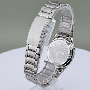 Pu&ograve; includere: Un orologio da polso argentato con cinturino in acciaio inossidabile. Il quadrante dell'orologio non &egrave; visibile, ma il retro dell'orologio &egrave; visibile, con il marchio "BIANCHI" e le parole "QUARTZ HIGH QUALITY STAINLESS STEEL" stampate.