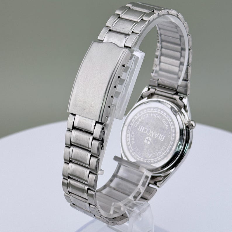 Pu&ograve; includere: Un orologio da polso argentato con cinturino in acciaio inossidabile. Il quadrante dell'orologio non &egrave; visibile, ma il retro dell'orologio &egrave; visibile, con il marchio "BIANCHI" e le parole "QUARTZ HIGH QUALITY STAINLESS STEEL" stampate.