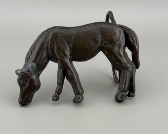 Hebilla de cinturón con forma de caballo pastando, diseño escultórico, tono bronce ecuestre.