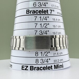 Pu&ograve; includere: Un braccialetto in metallo argentato &egrave; esposto su uno strumento di misurazione bianco EZ Bracelet Mini. Lo strumento presenta misure in pollici e centimetri, tra cui 7" (17,8 cm), 7 1/4" (18,4 cm) e 7 1/2" (19,1 cm).