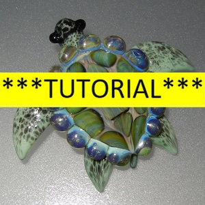 May include: A green and blue glass turtle with black eyes and a speckled shell. The turtle is a decorative piece of art.