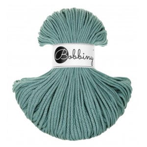 May include: A ball of teal-coloured Bobbiny cotton yarn. The yarn is tightly wound and has a textured appearance. The label on the yarn ball reads "Bobbiny" in a cursive font. This yarn is suitable for various crafting projects.