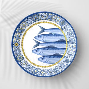 May include: A round ceramic plate with a blue and yellow decorative border. The plate features a central design of five blue fish arranged in a row, surrounded by a yellow rope-like border.