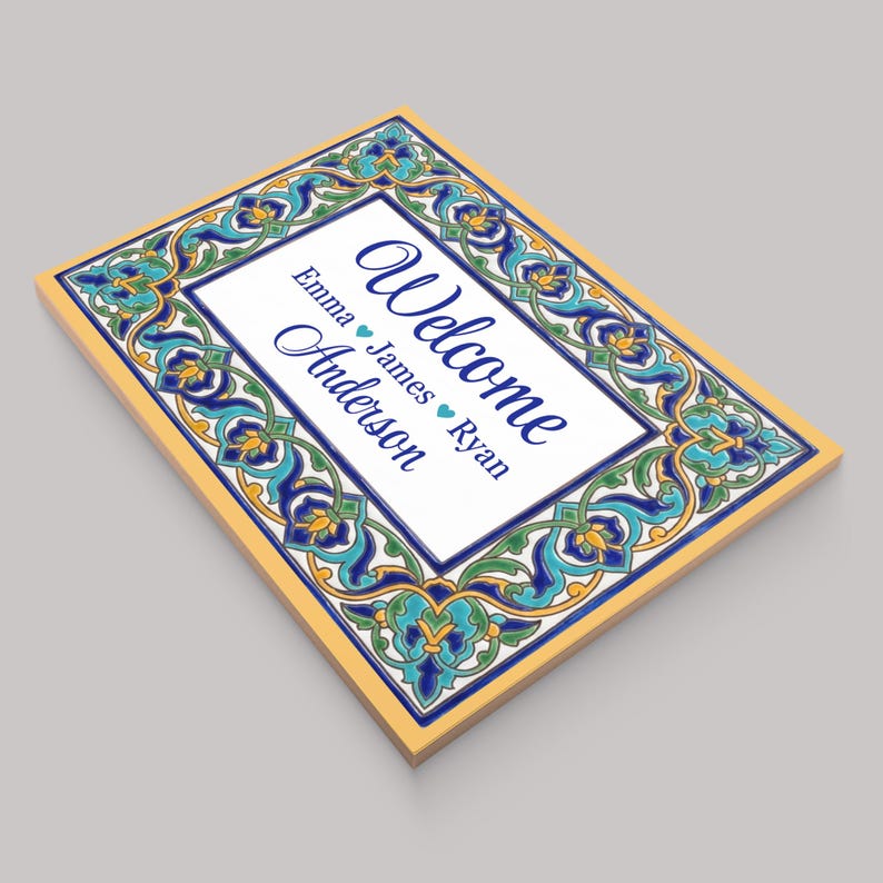 K&ouml;nnte beinhalten: Rechteckiges Willkommensschild mit dekorativem Rand in Blau-, T&uuml;rkis- und Gelbt&ouml;nen. Das Schild zeigt das Wort "Welcome" in eleganter Schrift sowie Namen. Das Schild hat eine wei&szlig;e Mitte und einen gelben Rand.