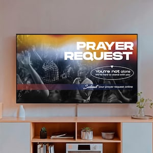May include: A television screen displays the words "PRAYER REQUEST" in white against a colorful background. Below, it reads "You're not alone, We're here to stand with you." The text "Submit your prayer request online" is also visible.