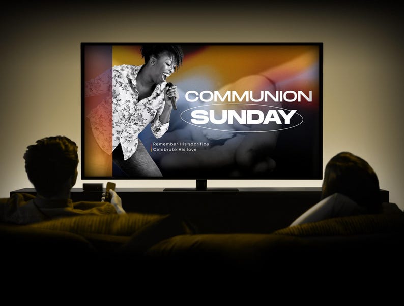 May include: A television screen displays the words "COMMUNION SUNDAY" in white, with a black and white image of a woman singing. The text "Remember His sacrifice | Celebrate His love" is also visible. Two people are sitting on a couch.