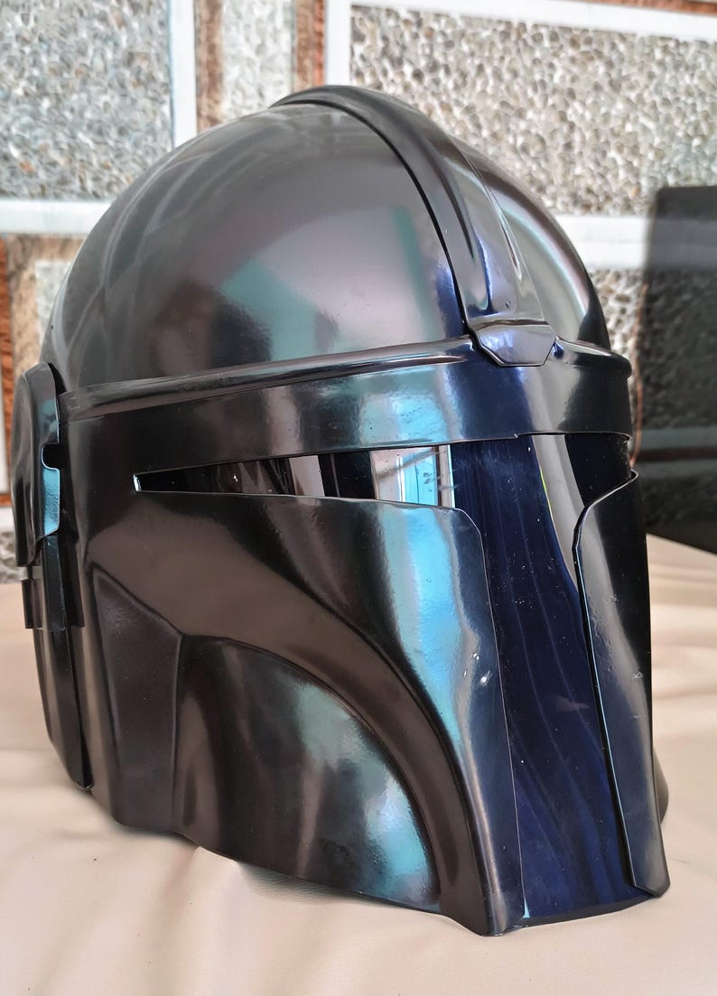 May include: A glossy black helmet with a distinctive visor and angular design. The helmet has a smooth, reflective surface and appears to be made of a durable material. The overall shape suggests a futuristic or sci-fi theme.