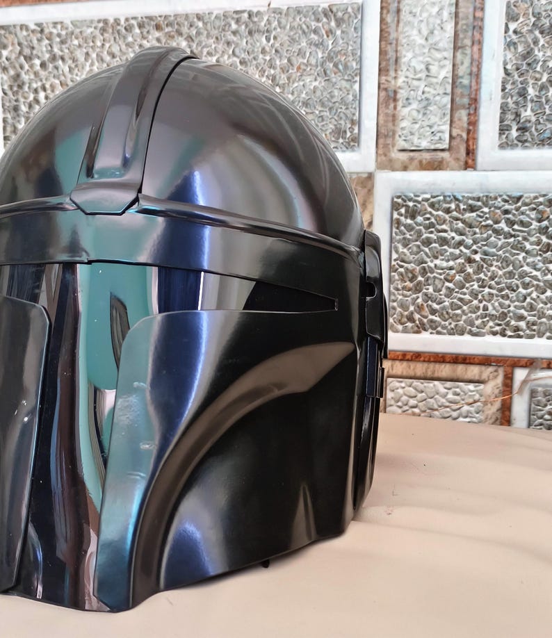 May include: A glossy black helmet with a distinctive visor and a rounded top. The helmet has a smooth, reflective surface and appears to be made of a durable material. The design suggests a futuristic or science fiction theme.