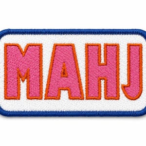 Peut inclure: Un écusson brodé rectangulaire avec un fond blanc et une bordure bleue épaisse. L'écusson présente le texte MAHJ en lettres roses grasses, chacune soulignée d'une fine bordure orange, centrées sur la surface en tissu blanc.