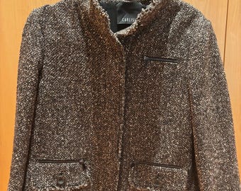 May include: A brown and white tweed jacket with a high collar and two front pockets. The jacket has a zipper pocket on the chest and is hanging on a black hanger. The brand name "CARLISLE" is visible on the label.