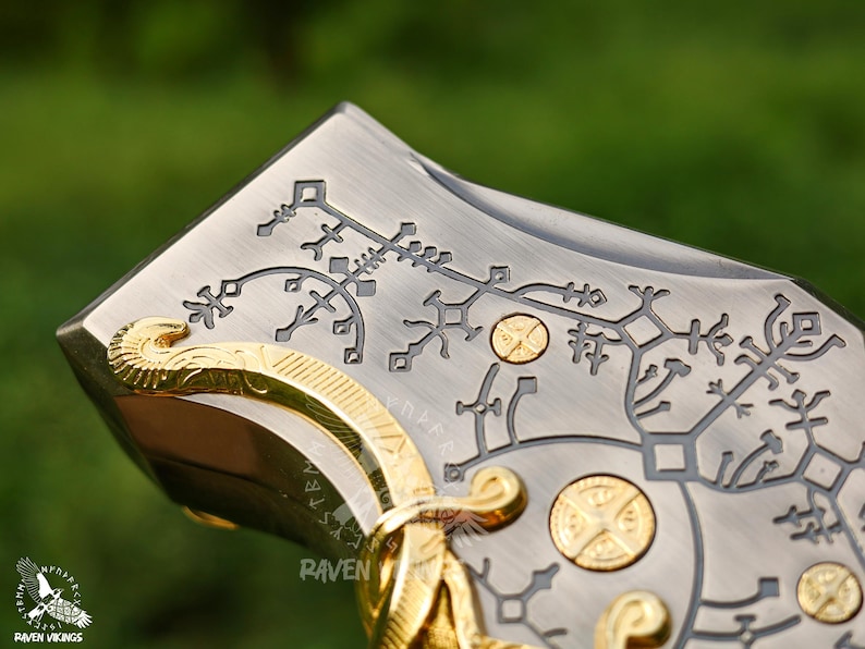 May include: Close-up of a silver and gold metal object with intricate engraved designs. The object features a decorative pattern and gold accents. The Raven Vikings logo is visible in the lower left corner.