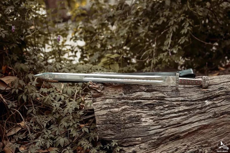 May include: A long, silver sword with a detailed handle and a black sheath rests on a weathered log. The blade is sharp and reflective, with a decorative handle. The sword is a historical or fantasy item.